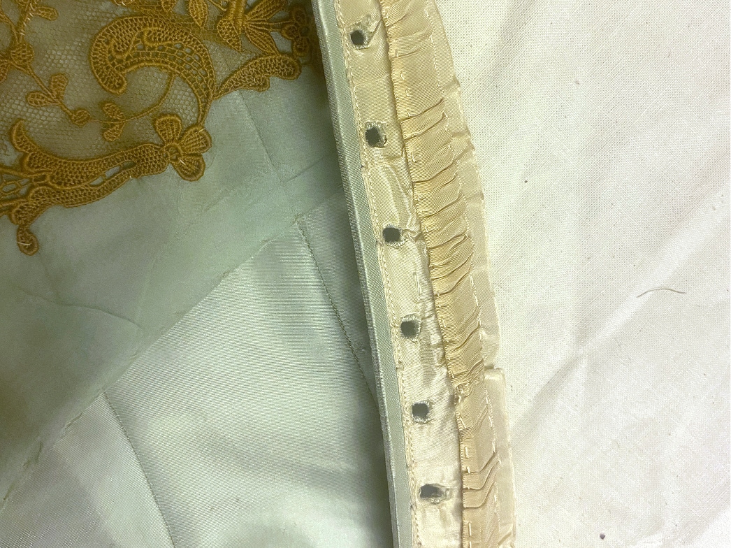 A close-up of several eyelets down the edge of the interior of a bodice.