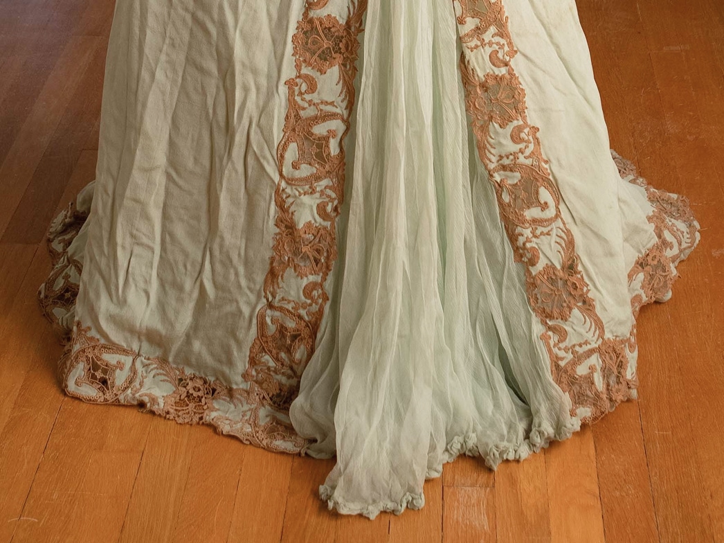 The bottom hemline of a silk dress features a gore insert of transparent fabric, with lace appliqué along the edges.