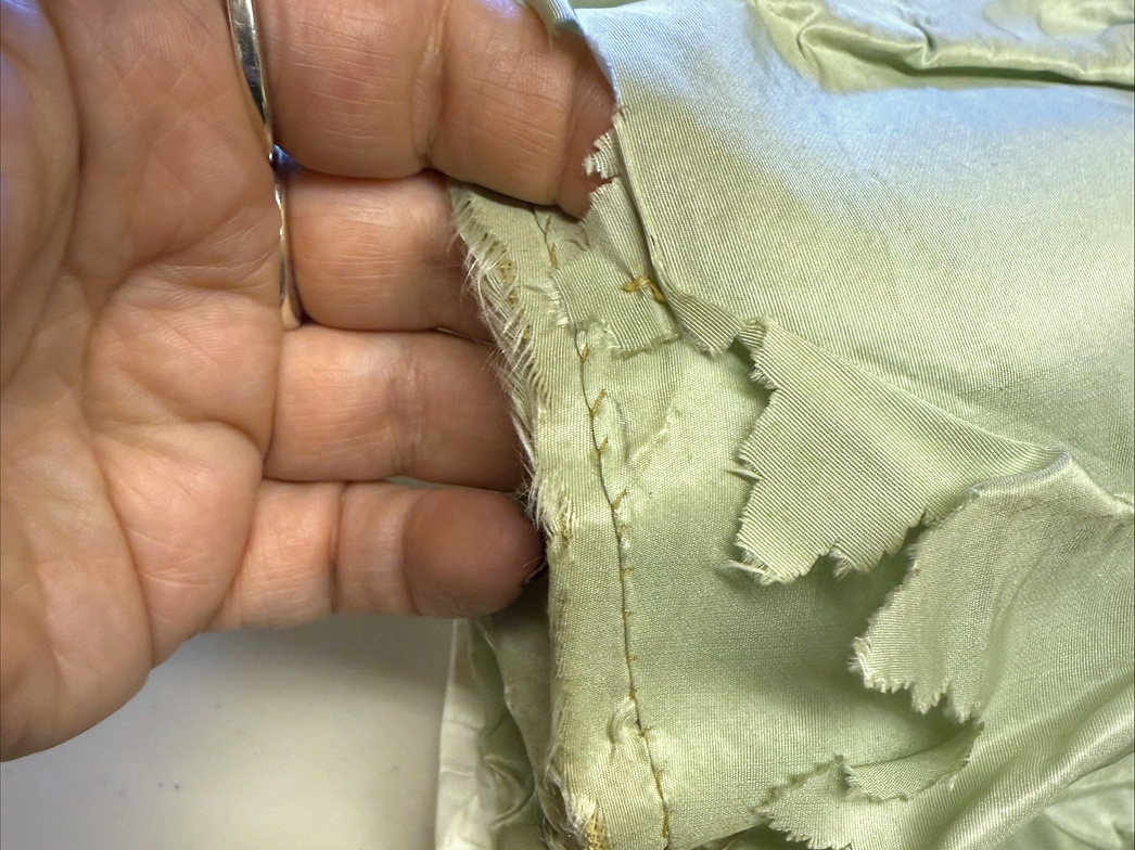 A close-up of the underlayers of the skirt shows a hand holding several layers of underskirts including one layer with jagged cutouts.