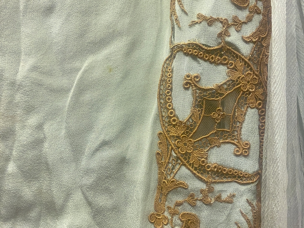 A detail of the lace shows an intricate design pattern repeating.