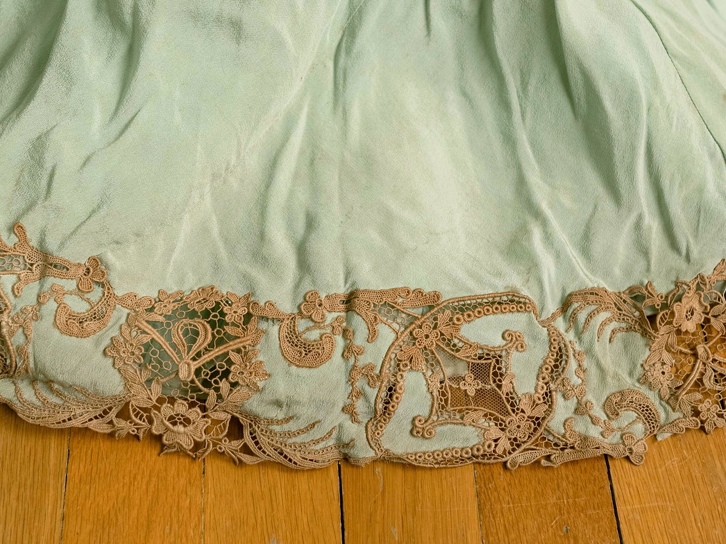 The bottom hemline of a silk dress features appliqué lace atop the silk edges.