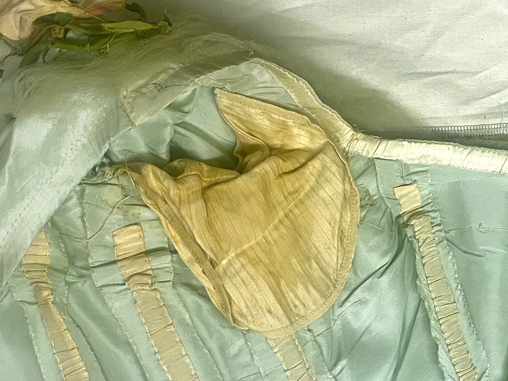 A close-up of the interior underarm area of the dress shows yellowing silk pads attached.