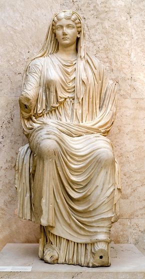 Ancient marble statue of a seated Roman empress wearing a flowing garment. The statue is damaged with the lower right arm missing.