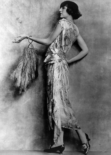 A 1920s flapper wearing a satin dress strikes a graceful pose.