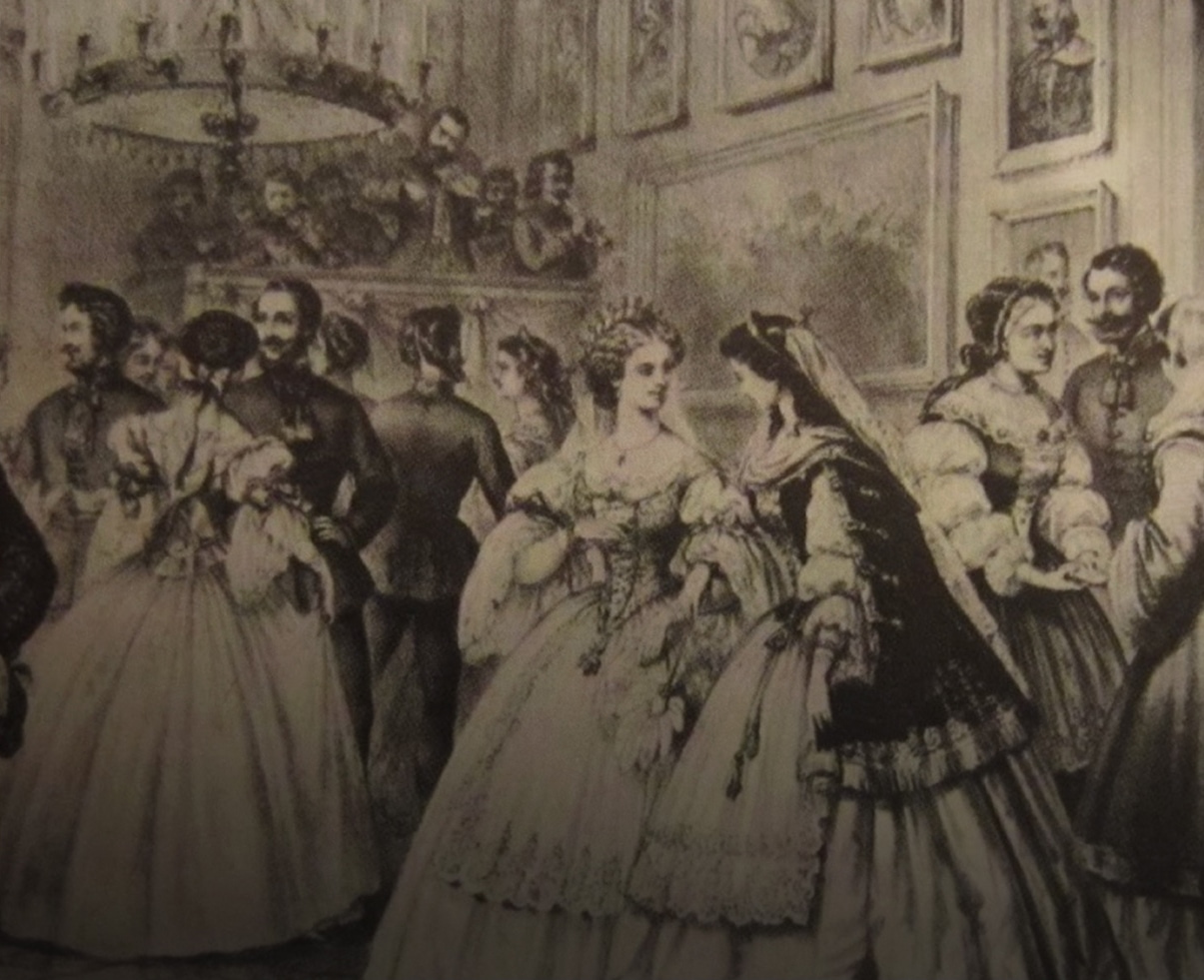 Ladies in fashionable period dress mingle with gentlemen in military regalia at an aristocratic ball. A small orchestra plays in the background.