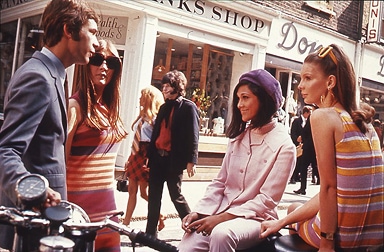 Stylish men and women hang out in front of London shops.