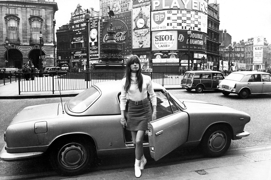 The French singer and actress, Francoise Hardy, steps out of sports car wearing a turtleneck sweater, mini-skirt, and white leather boots, in London’s Piccadilly Square.