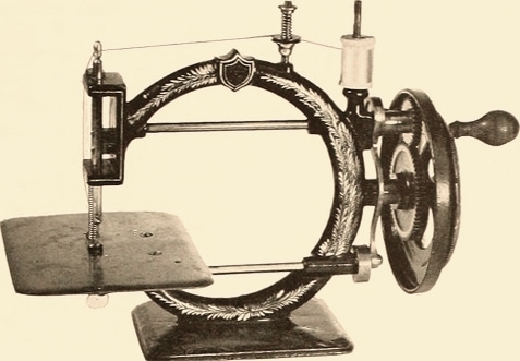 A vintage sewing machine with crank wheel and crescent shaped body.