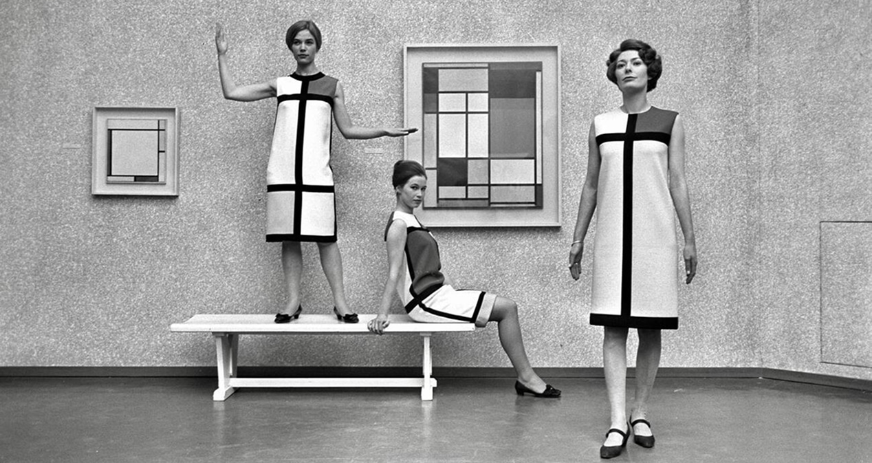 Three women model Mondrian print dresses in an art gallery displaying the artist’s paintings.